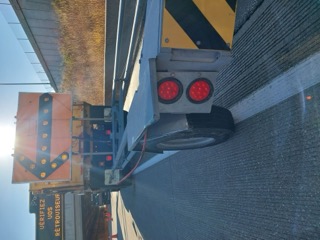 Truck with flashing red lights and yellow reflective panels. Text reads: VÉRIFIEZ JOS RÉTROUVEUR