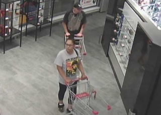 Person pushing a shopping cart, wearing a graphic t-shirt and black leggings