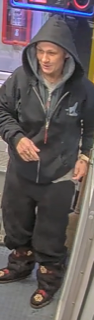 Man in a black hoodie and sweatpants, looking down.