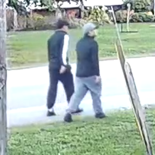 Two people walking on a paved path.