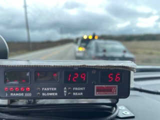 Speedometer displaying 129.56. Directional signage.