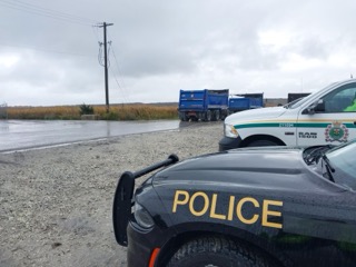 Police vehicle, black and white, parked on a gravel road.