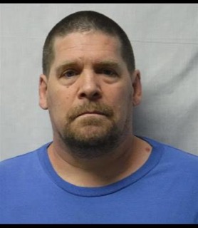 Man with closely-cropped hair and a goatee, wearing a blue t-shirt.