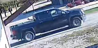 Black pickup truck parked on gravel.