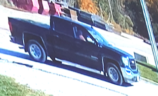 Black pickup truck parked on gravel.