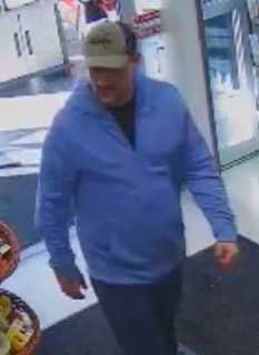 Man in a blue sweatshirt and black pants, wearing a baseball cap