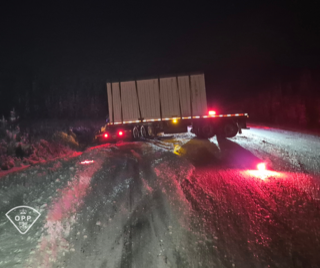 Semi-truck trailer with flashing red and yellow lights on a snowy road.