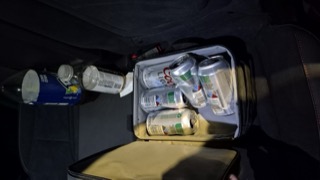 Black cooler filled with canned drinks and a bottle of lemon citrus water