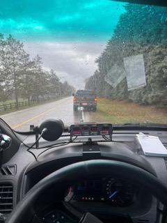 Dashboard view through rain-streaked windshield.