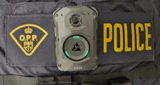 O.P.P. crest and POLICE text on a black uniform. Body-worn camera attached.
