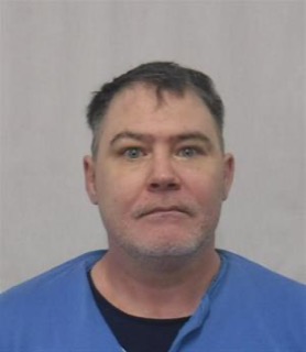 Man in blue scrubs, looking directly at the camera