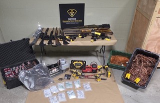 Firearms, ammunition, and tools on a table.