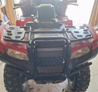 Red four-wheeler with a black front brush guard