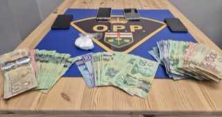 Canadian currency and a bag of white powder on a table. O.P.P. logo in the background.