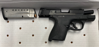 Black pistol and two magazines on a target with bullet holes