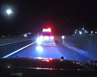 Police car with flashing red and blue lights on a dark road