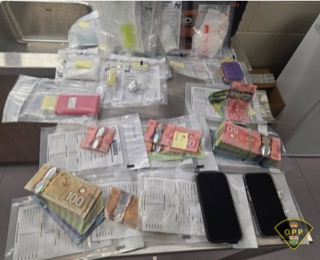 Canadian currency in small packages, two smartphones, and small plastic bags.