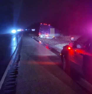 Emergency vehicles with flashing lights on a wet road.