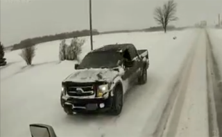 Black pickup truck driving on a snow-covered road