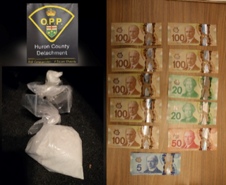 White powder in a plastic bag, Canadian currency stacked on a wooden surface.