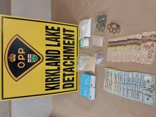 OPP Kirkland Lake Detachment logo. Stack of US currency. Plastic baggies. Small packages.