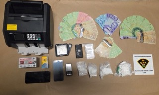 Cash, small baggies, two boxes of ammunition, a cash register, a cell phone, a scale, and a document reading &quot;Norfolk and Haldimand Community Street Crime Unit.&quot;