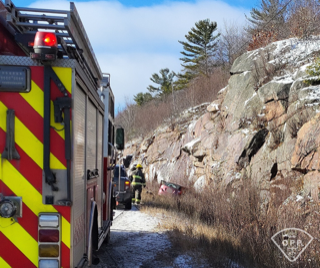 Firefighters working near a rocky hillside.