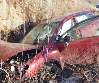 Damaged red car in tall grass