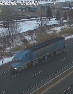 Blue semi-truck driving on a snowy road