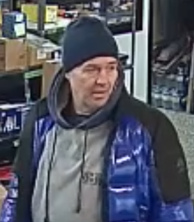 Man wearing a black beanie and blue puffer jacket.