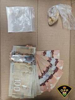 Stacks of Canadian currency, including $100 and $50 bills. Small bag of a white powdery substance.