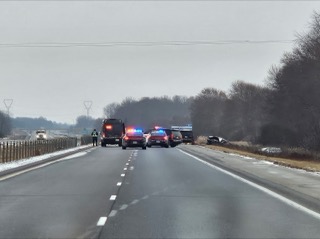 Damaged vehicle on the shoulder, police cars and emergency responders on the highway