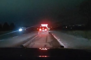 Towing truck with flashing red and white lights on a dark road