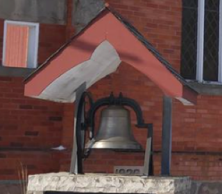 Bronze bell under a red roof.