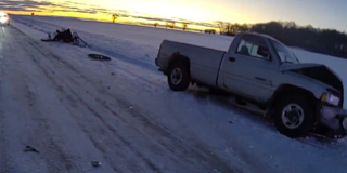 Damaged pickup truck on icy road, debris scattered
