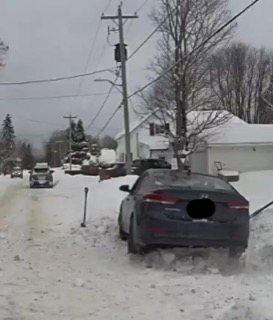 Dark blue car partially buried in snow.