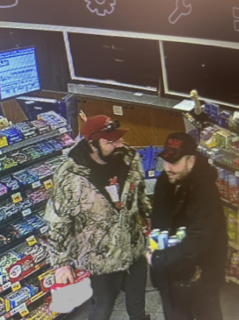 Two men in hats and jackets talking in a convenience store.