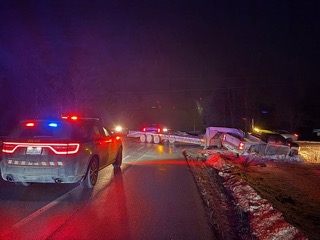Damaged vehicle and police car at night.