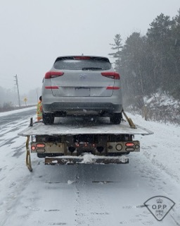 Black SUV being towed on a snow-covered road.