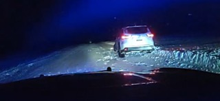 White SUV driving on a snowy road at night