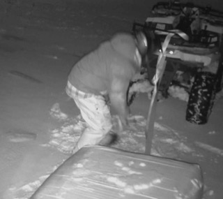 Person shoveling snow near a snowmobile.
