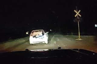 Damaged white car on train tracks, unclear surroundings