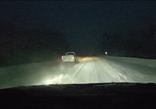 Pickup truck headlights illuminate a dark road