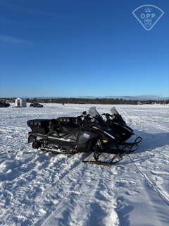 Black snowmobile, OPP branding, snowy landscape