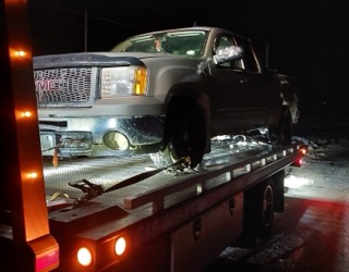 Damaged gray pickup truck on a flatbed tow truck