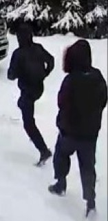 Two figures in dark clothing standing in snow.