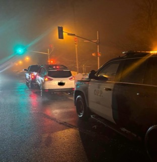 Police vehicles with flashing lights on a wet road.