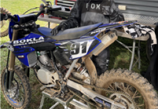 Blue dirt bike covered in mud. 31 visible on the front number plate.